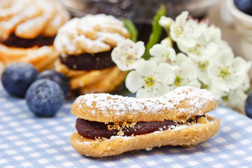 Eclairs with blueberry marmalade. Blooming apple twig