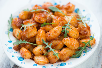 Gnocchi with tomato sauce and arugula lettuce, close-up