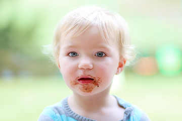 Cute toddler girl eating chocolate