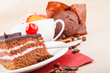 Chocolate cherry cake and cup of coffee with cupcake