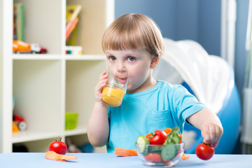 baby boy dinking juice at table in children room