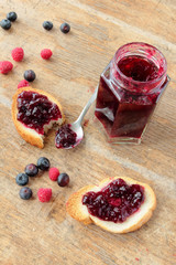 Glass jar of sweet raspberry jam. Crunchy bread with jam.
