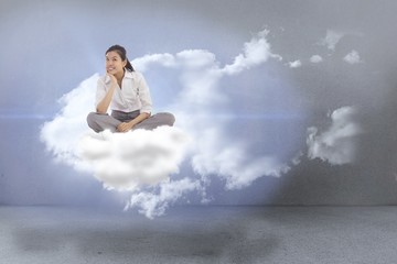 Composite image of businesswoman sitting cross legged thinking