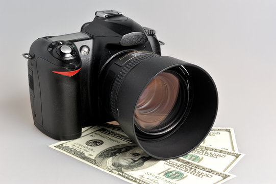 Photo camera with dollars on gray