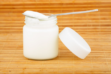 the jar with yoghurt and spoon on a straw mat