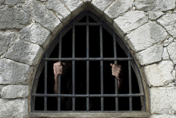 prisoner behind bars of a dark prison
