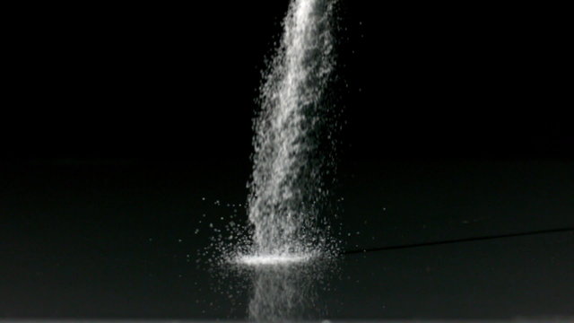 Salt pouring against black background