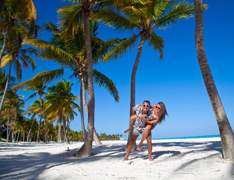 Man giving piggyback ride to girlfriend at the Caribbean beach