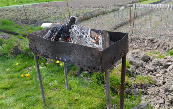 Brazier with burning firewood on a kitchen garden