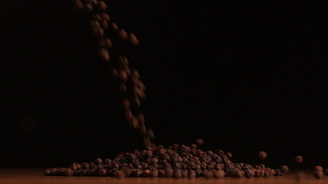 Pepper corns pouring on black background