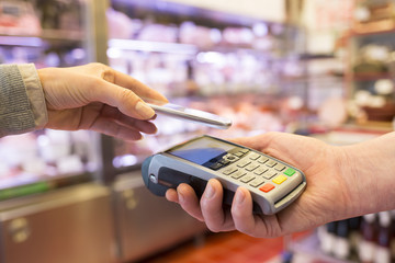 Woman paying with NFC technology on mobile phone, in supermarket