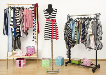 Closet with striped clothes arranged on hangers and a mannequin