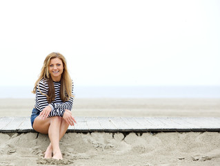 Happy young woman sitting at the beach