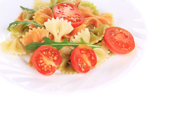 Colored farfalle on white plate with tomatoes.