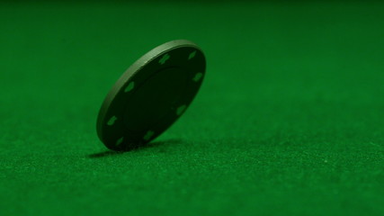 Green chip spinning on casino table - Powered by Adobe