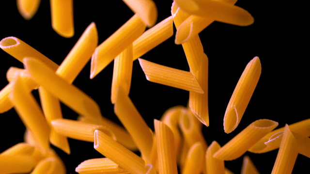Penne bouncing against black background