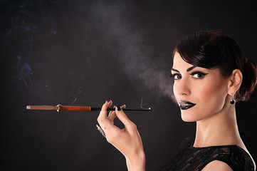 Obraz premium attractive woman with dark makeup smokes a cigarette
