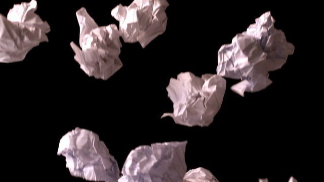 Crumpled paper falling against black background