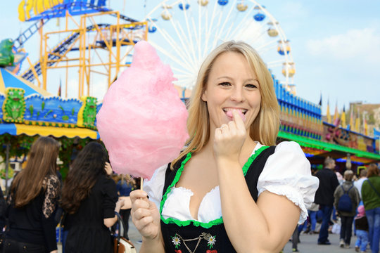 Frau im Dirndl auf Oktoberfest isst Zuckerwatte