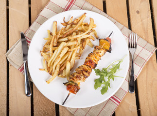 plate of French fries with a skewer of meat