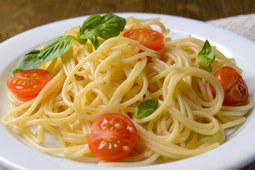 Delicious spaghetti with tomatoes on plate on table close-up
