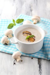 Mushroom soup in white pot, on napkin,  on wooden background