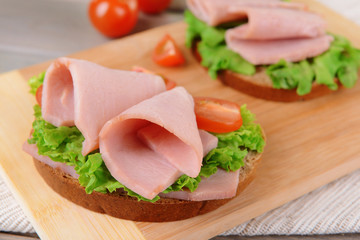 Delicious sandwiches with lettuce and ham on table close-up
