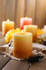 Beautiful candles with flowers on wooden background