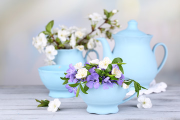 Beautiful spring flowers in cups on wooden table