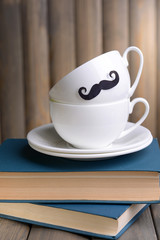 Cup with mustache on table on wooden background