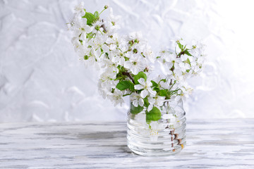 Beautiful fruit blossom in jar on table on grey background