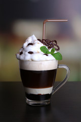 Glass of coffee on color wooden table, on dark background