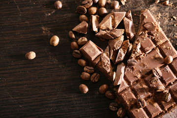 Chopped bar of chocolate on wooden background