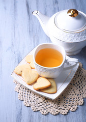Lavender cookies and cup of tasty tea on color wooden