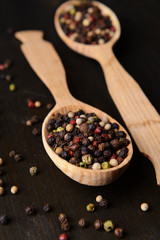 Spice pepper in spoons on wooden background