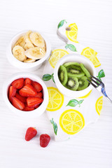 Various sliced fruits in bowls on table close-up