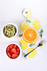 Various sliced fruits in bowls on table close-up