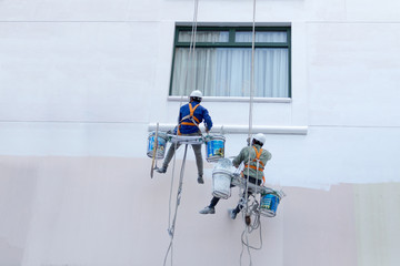 Two worker are painting the color in high buildings - Rise occup