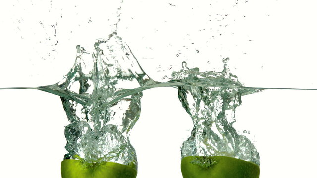 Apple halves plunging into water on white background