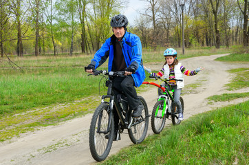 Naklejka premium Happy father and child on bikes, family cycling ourdoors