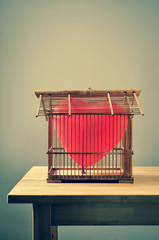 heart-shaped balloon in an old birdcage