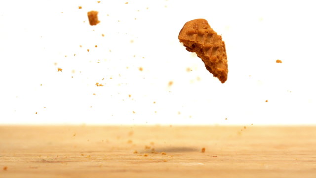 Biscuit falling and breaking on wooden table
