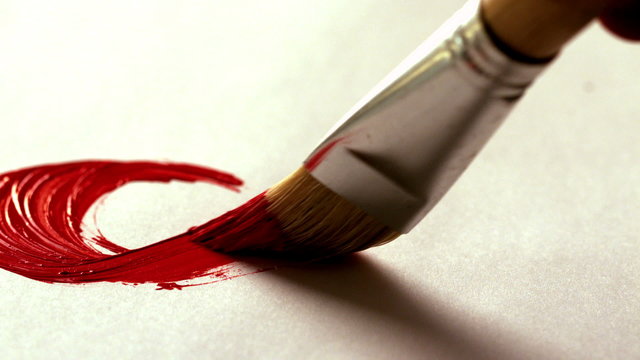 Painter painting with red paint and paintbrush