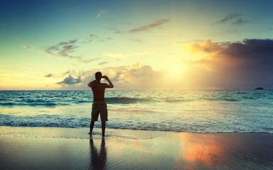 young man on the beach take photo on mobile phone