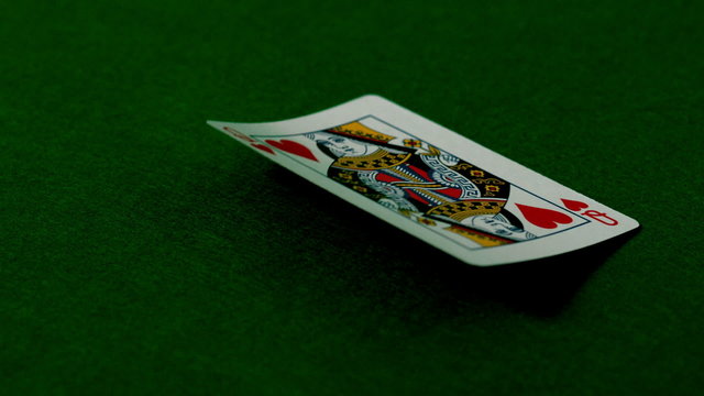 Queen of hearts falling on casino table