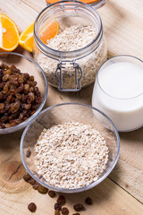 Bowl of oats, raisins cup of milk on the wooden table
