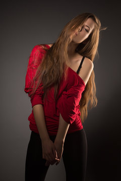 Beautiful young model in red posing on dark background.