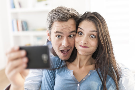 cheerful couple taking a humoristic selfie with a smartphone