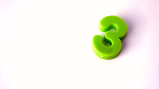 Number three falling onto white surface