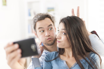 cheerful couple taking a humoristic selfie with a smartphone